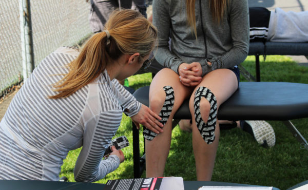 Student taping athlete knees