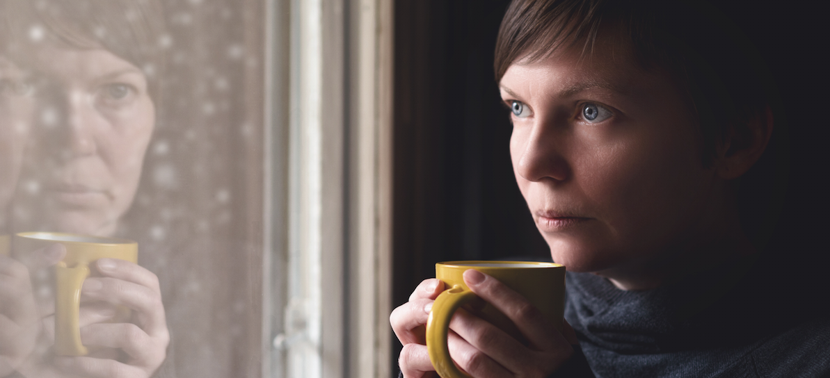 Woman drinking coffee starting out the window